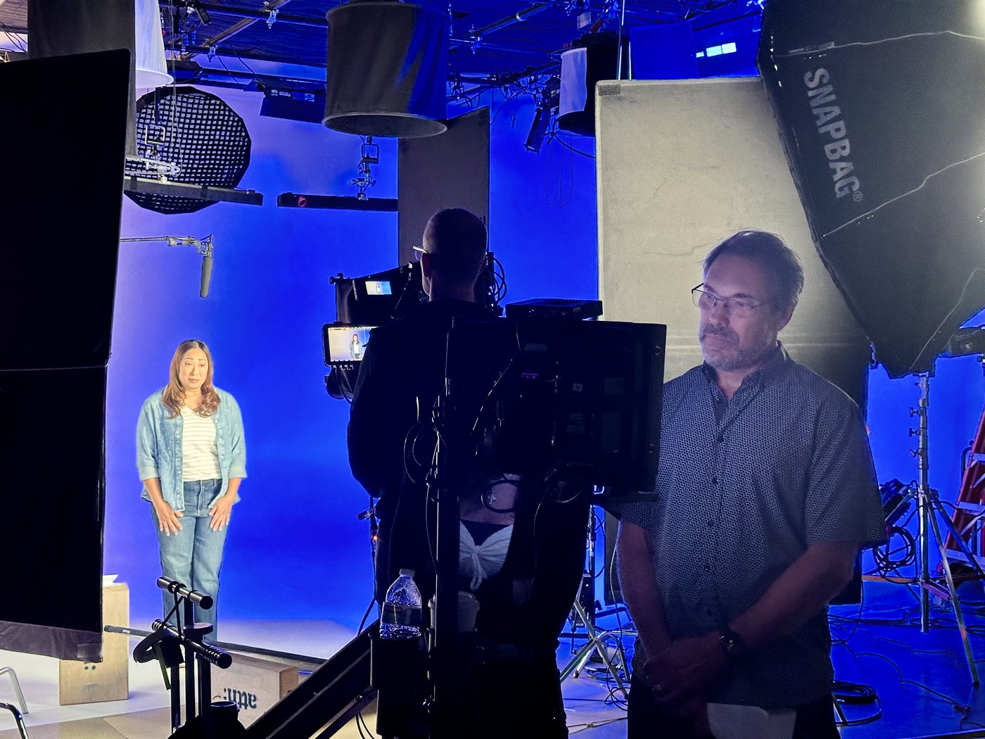 Jake Zortman on set, directing an interview on a blue cyc stage